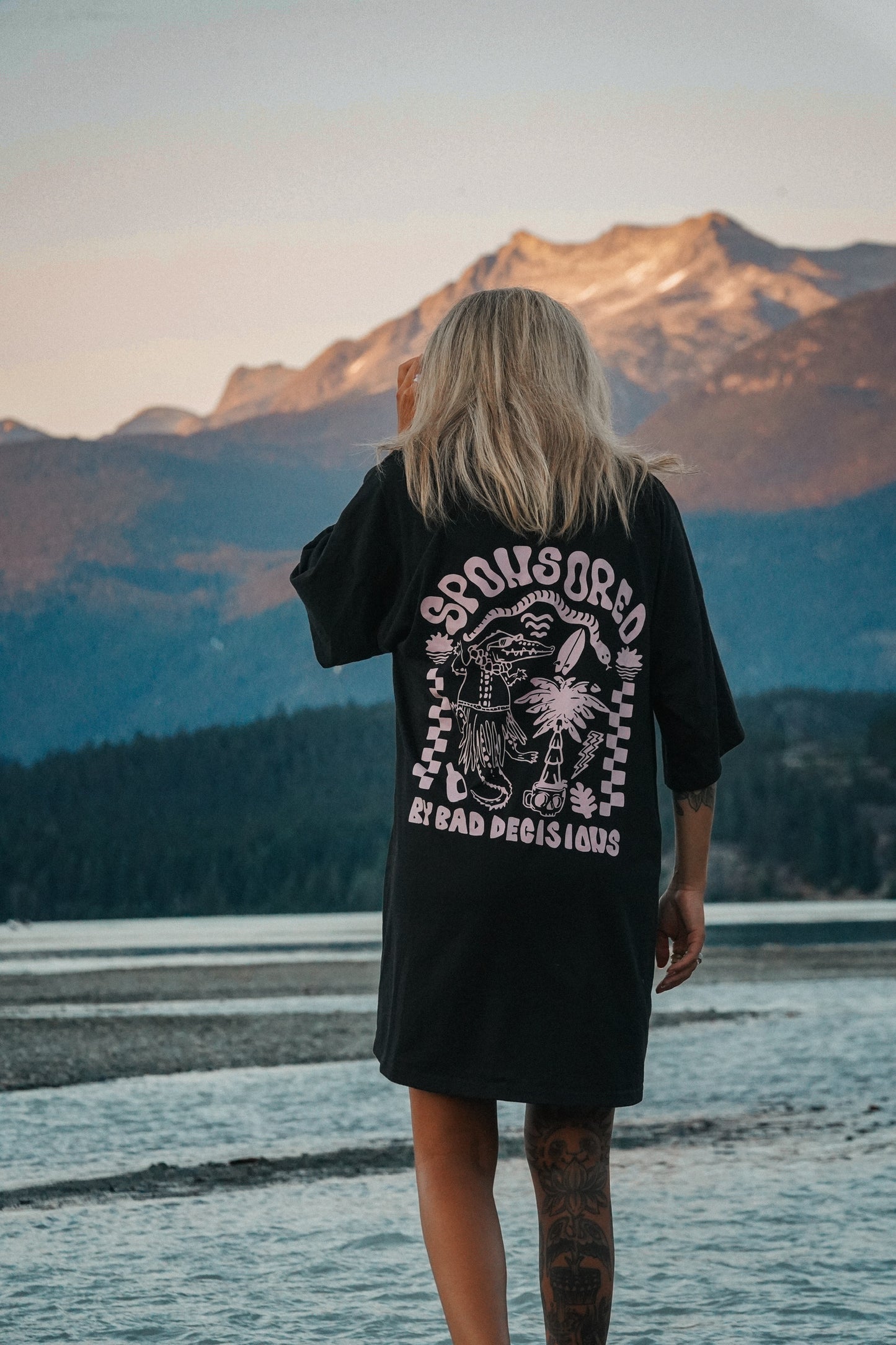 Black cotton T-shirt dress with bold graphic print worn in a beach and mountain summer setting