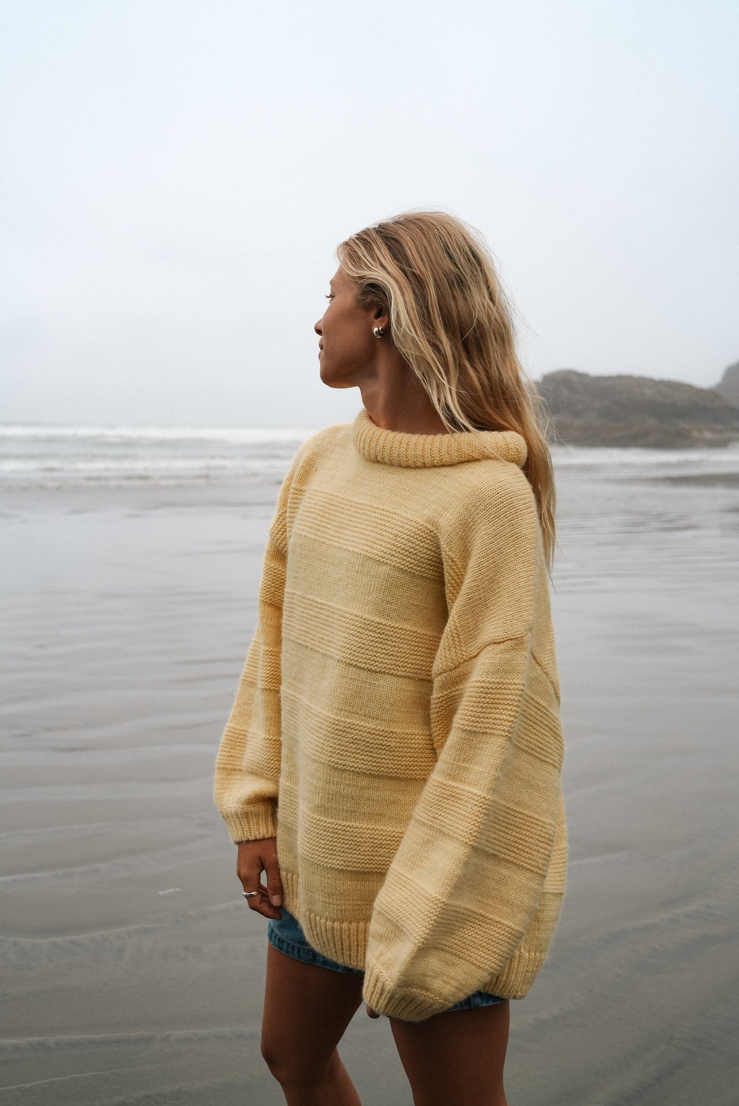 Oversized butter yellow wool sweater with textured tone-on-tone stripes and round collar, perfect for cozy beach evenings