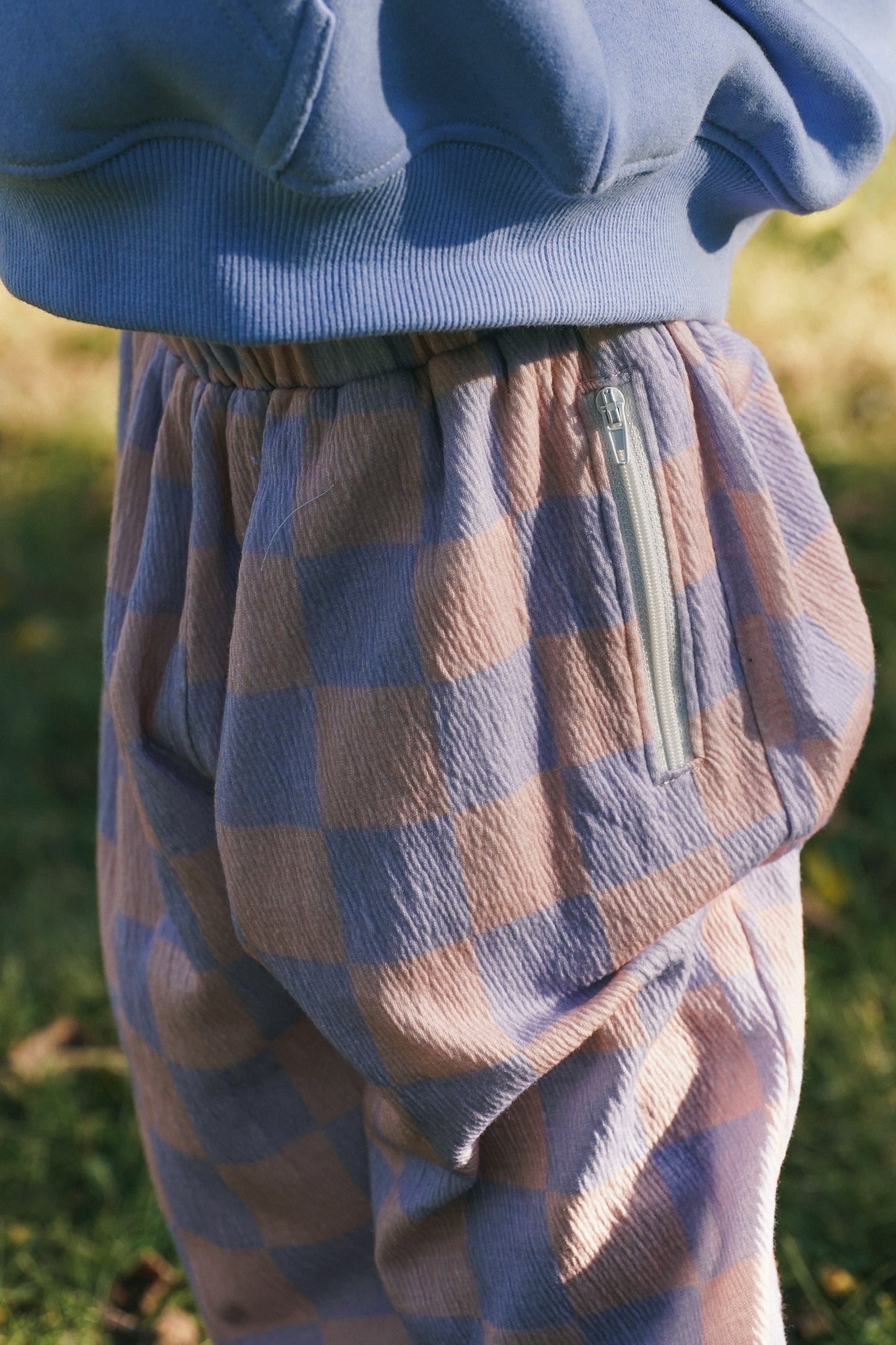 Child wearing Mist Checkered cotton pants with pink and blue pattern in a summer style