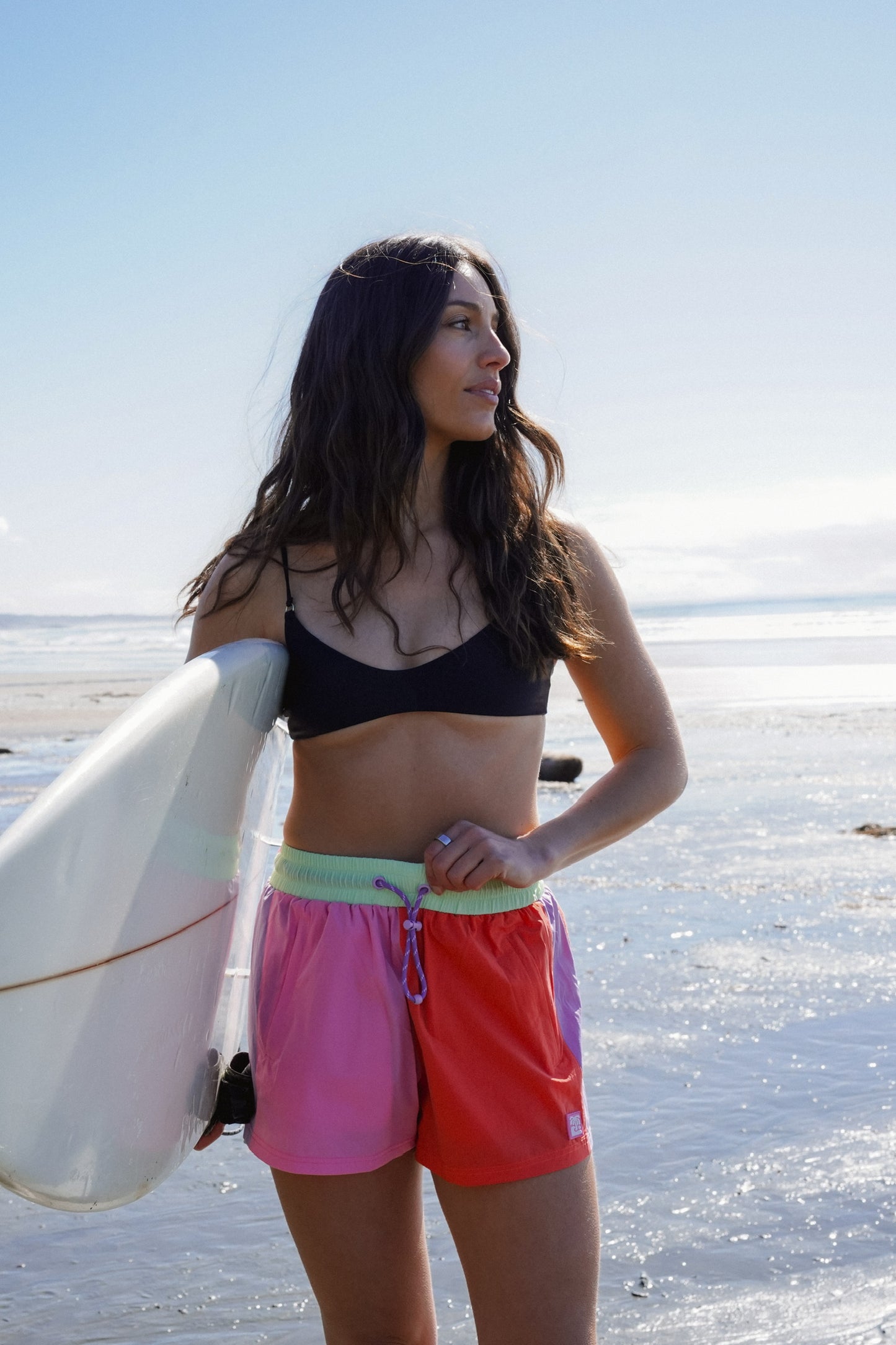 Woman wearing lightweight active shorts with relaxed fit and surf inspired summer design at the beach