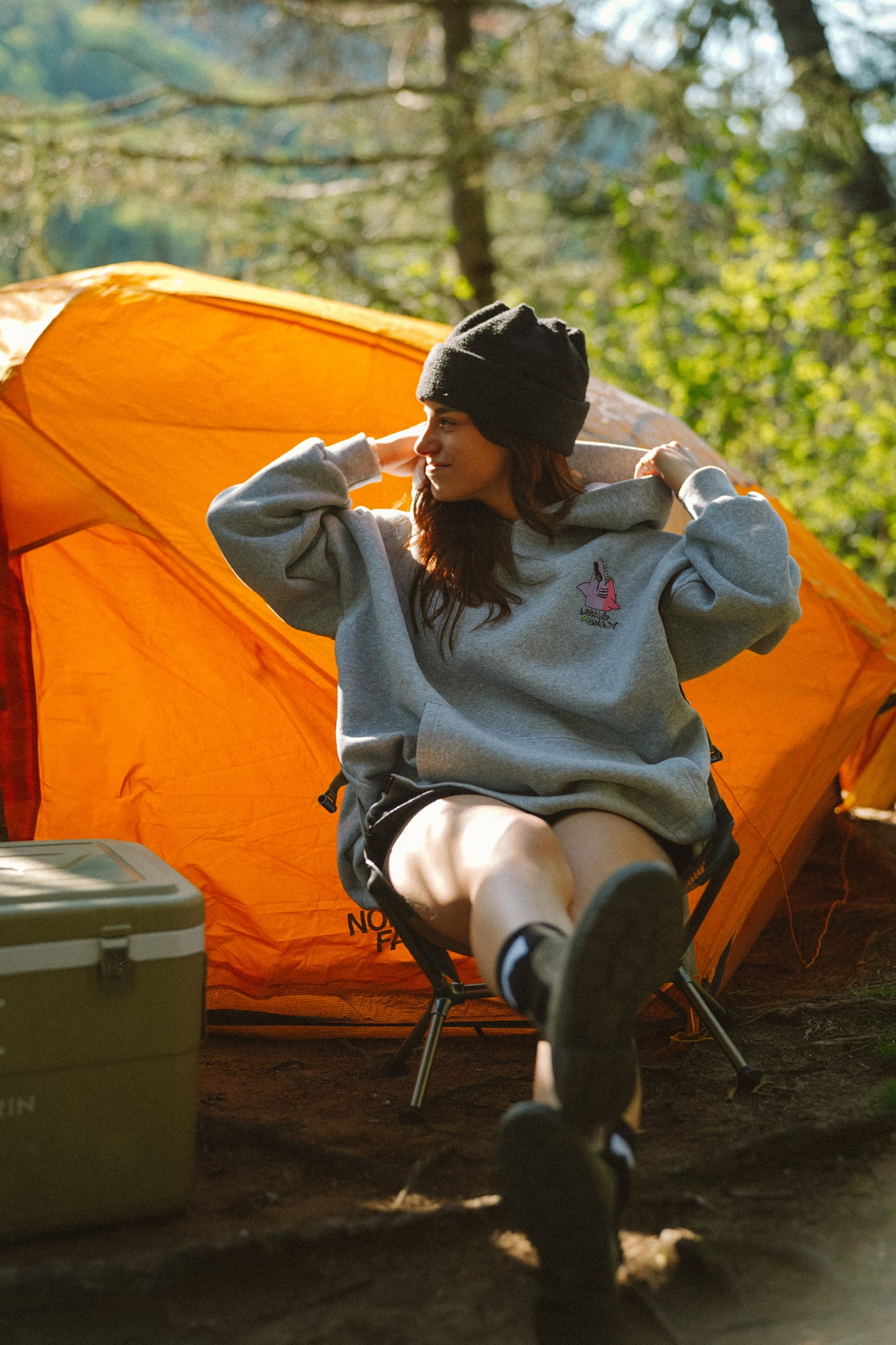 Woman wearing cotton oversized hoodie with Locals Only design in a relaxed camping setting