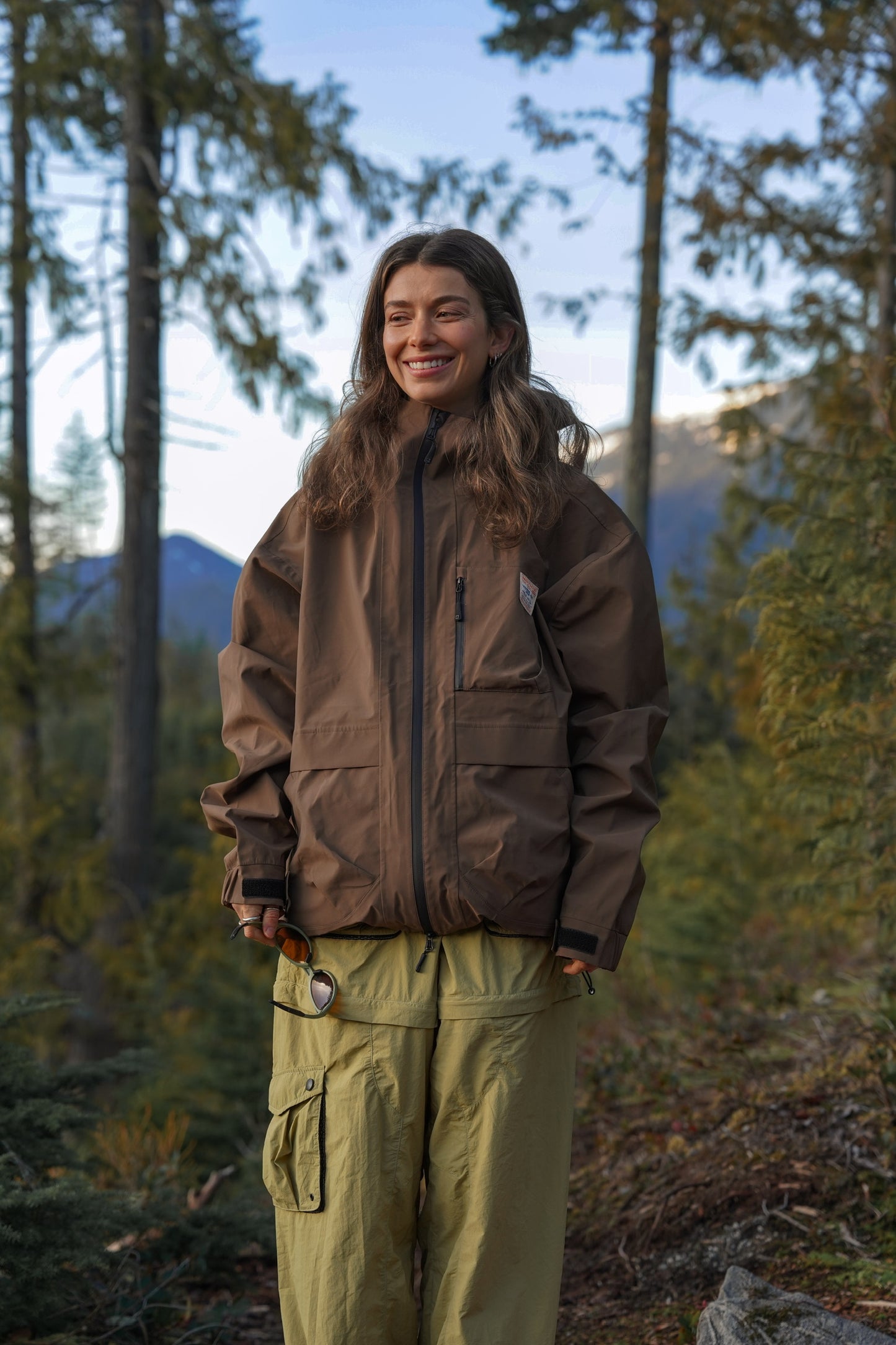 Women's espresso brown waterproof hiking rain jacket worn outdoors in a forest