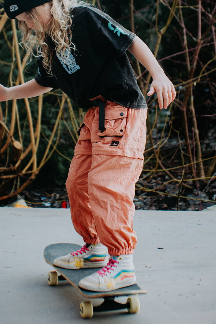 Kids dusty coral convertible hiking pants with zip-off legs and cargo pockets