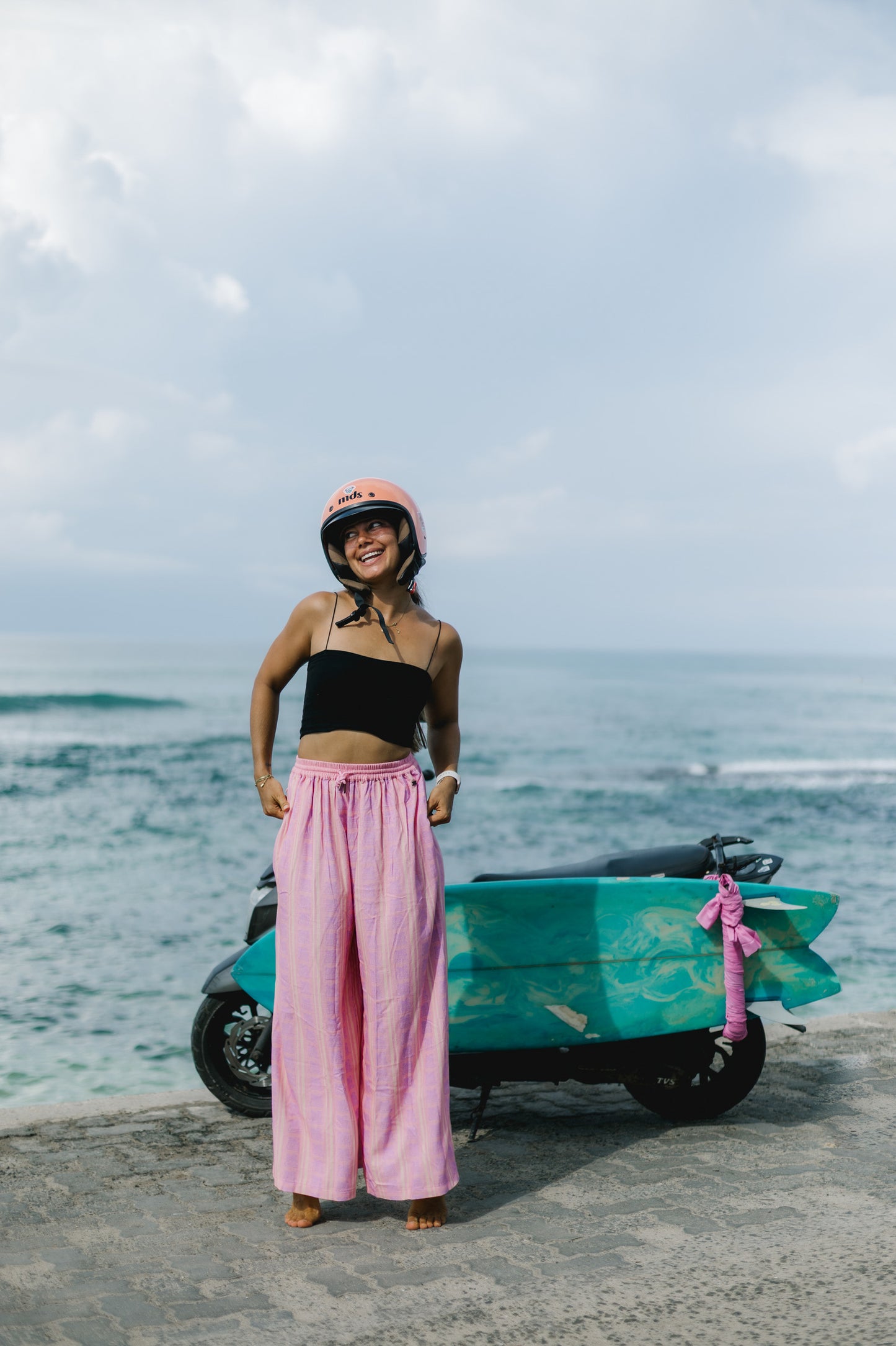 Pink boho pants in lightweight linen fabric styled for a beach day outfit with coastal summer vibes