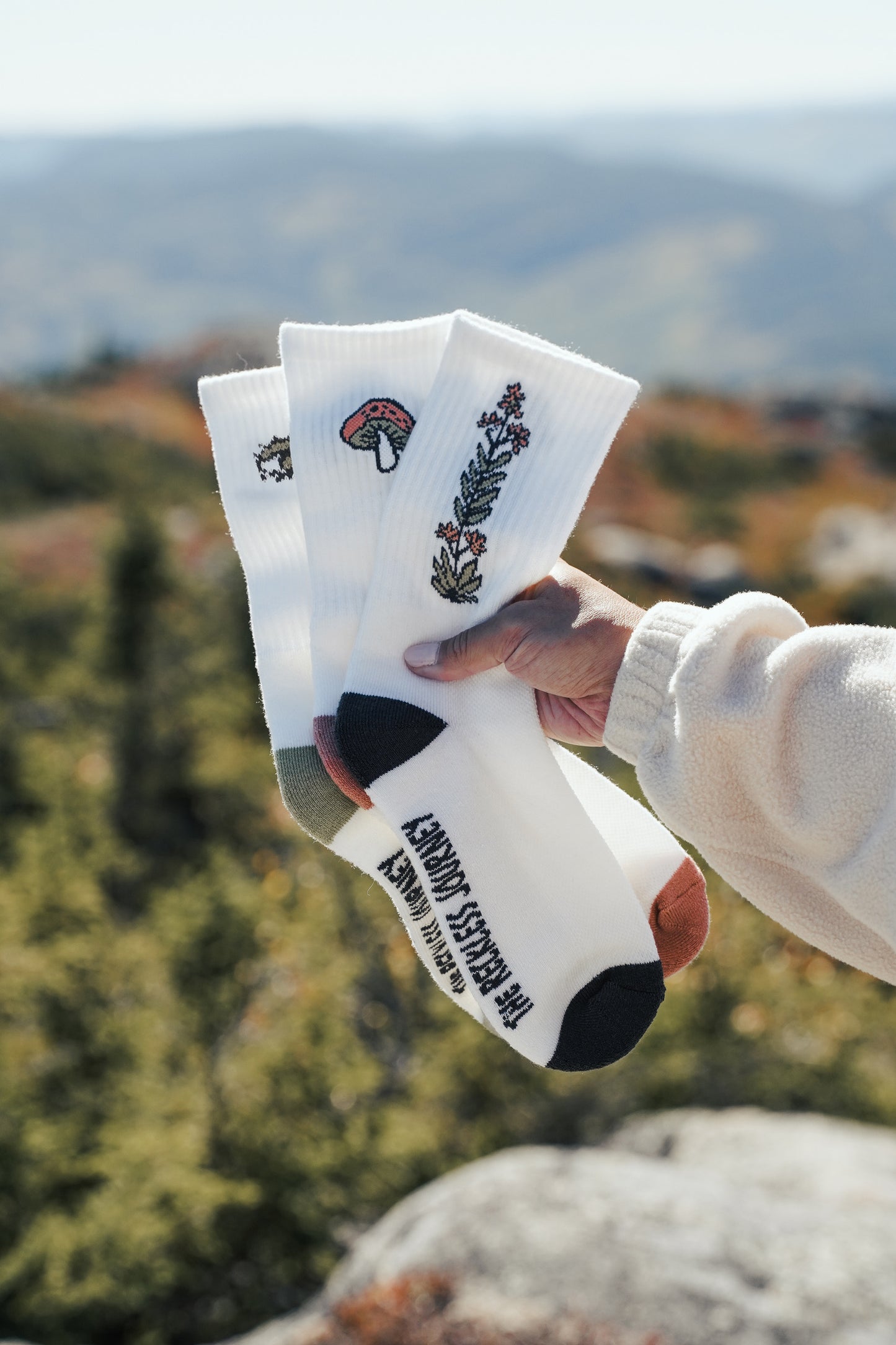 White merino wool crew hiking socks with embroidered floral and mushroom designs