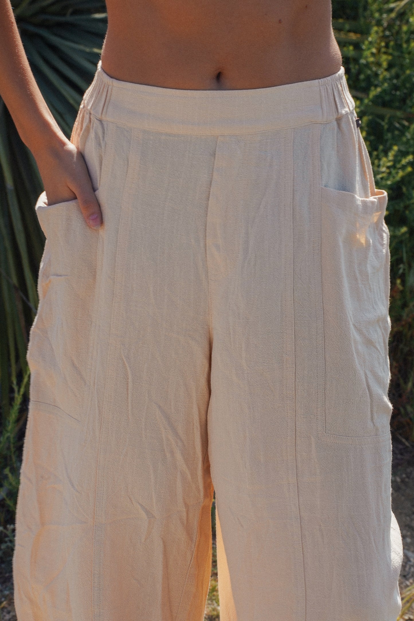 Sand-colored linen barrel pants highlighting the relaxed fit, functional side pocket and lightweight natural fabric