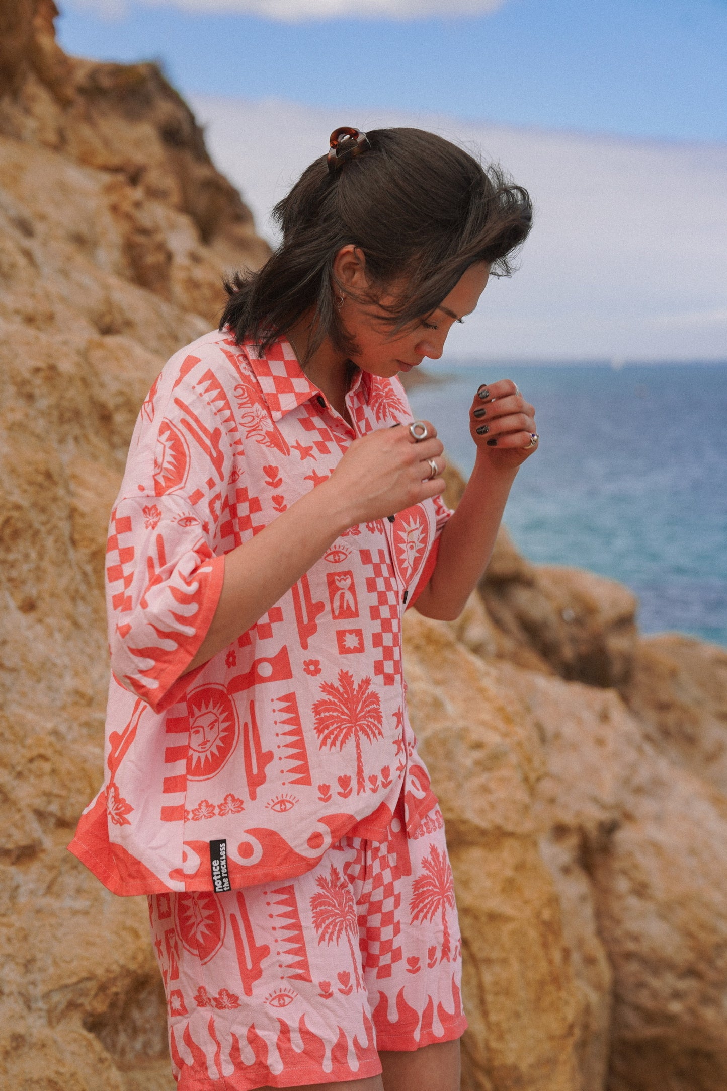 Women's patterned linen shirt in pink and red with graphic details on the front and back, designed for breathable comfort and effortless vacation wear