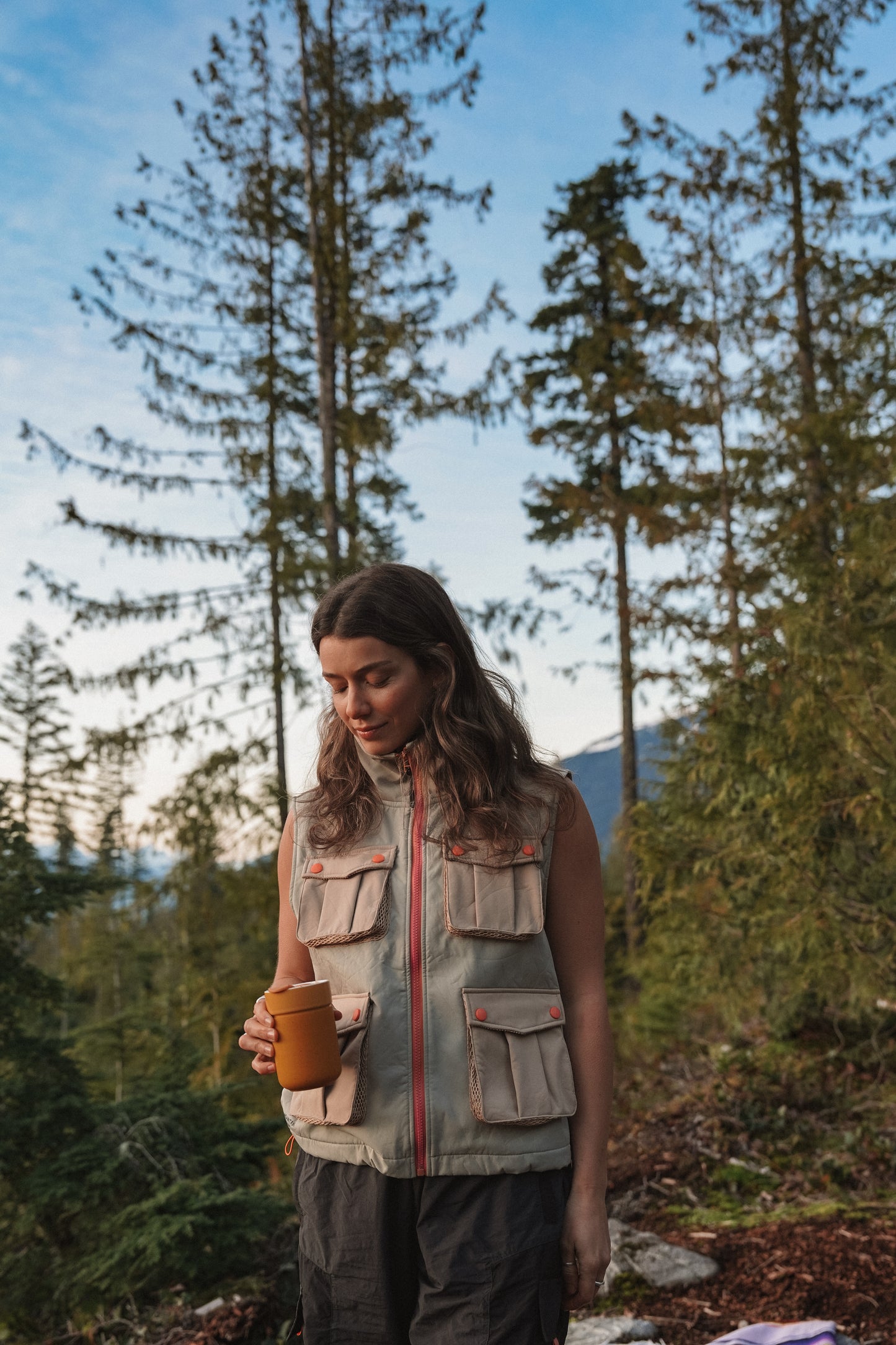 Woman wearing Summit softshell hiking vest in tan and beige with front cargo pockets outdoors