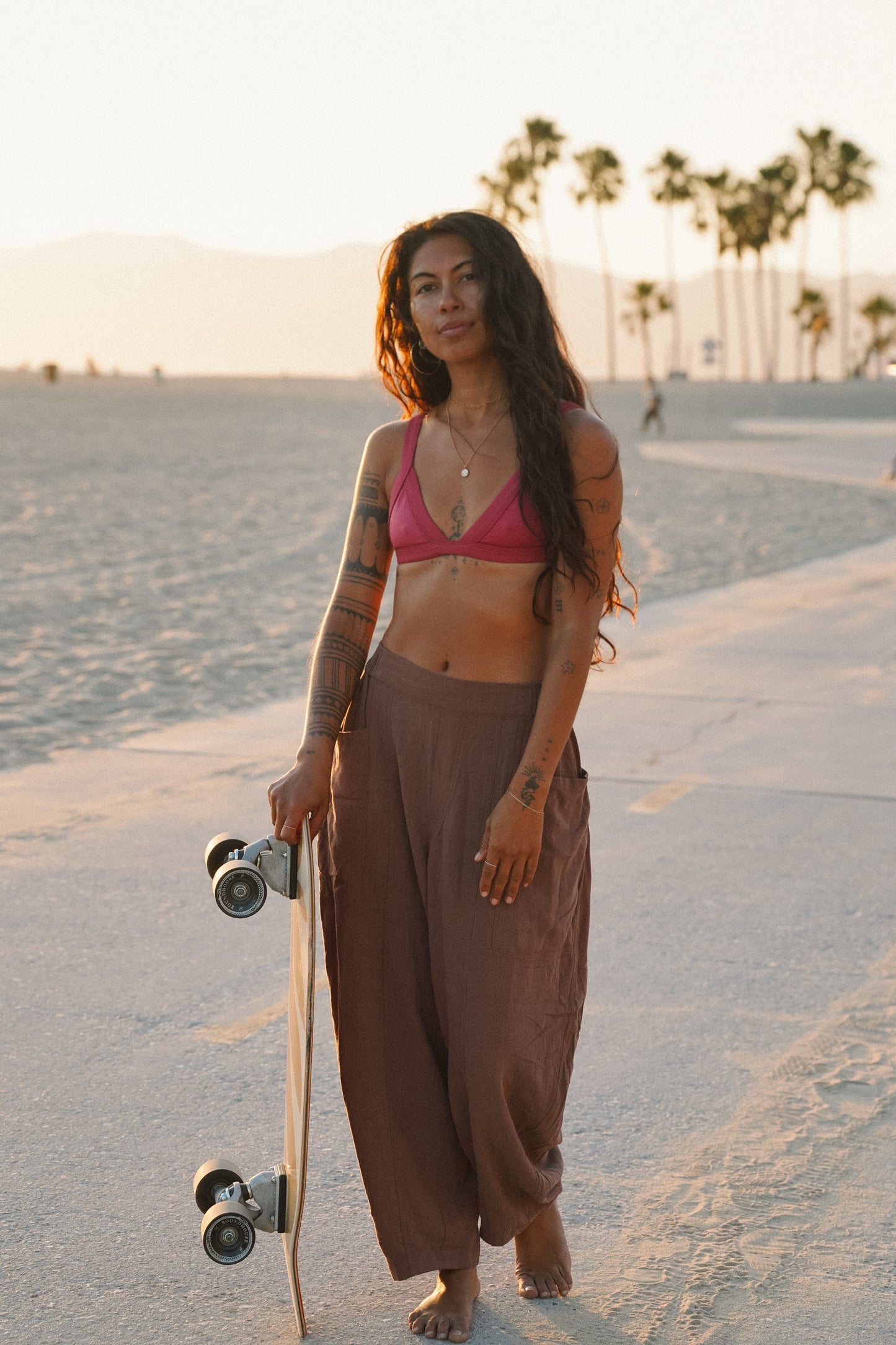 Women's brown linen barrel pants with a relaxed wide-leg silhouette, elastic waistband and oversized side pockets, styled for a laid-back beach lifestyle