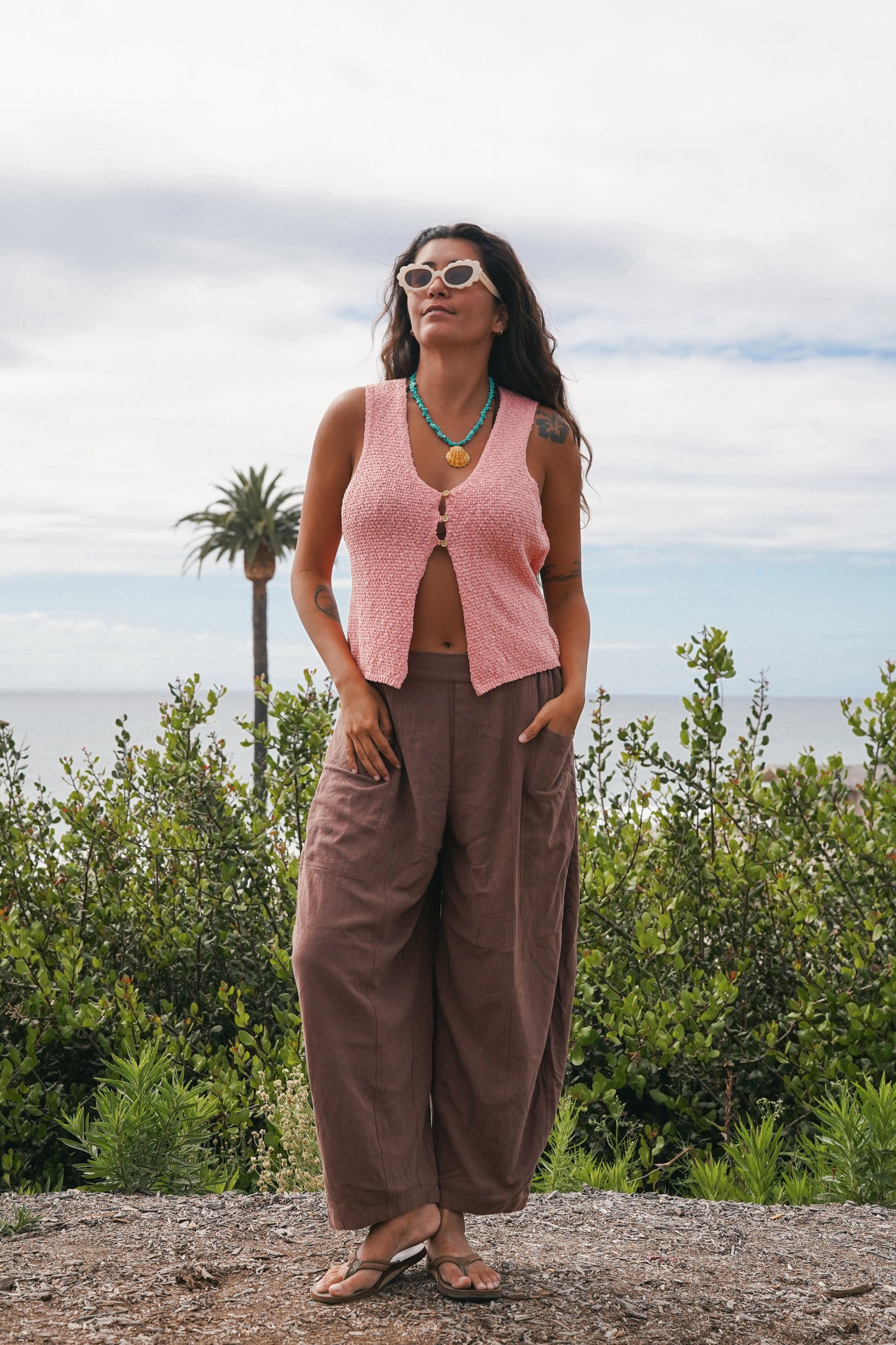 Women's brown linen barrel pants with a loose, flowy silhouette and functional pockets, styled with a boho-inspired outdoor look