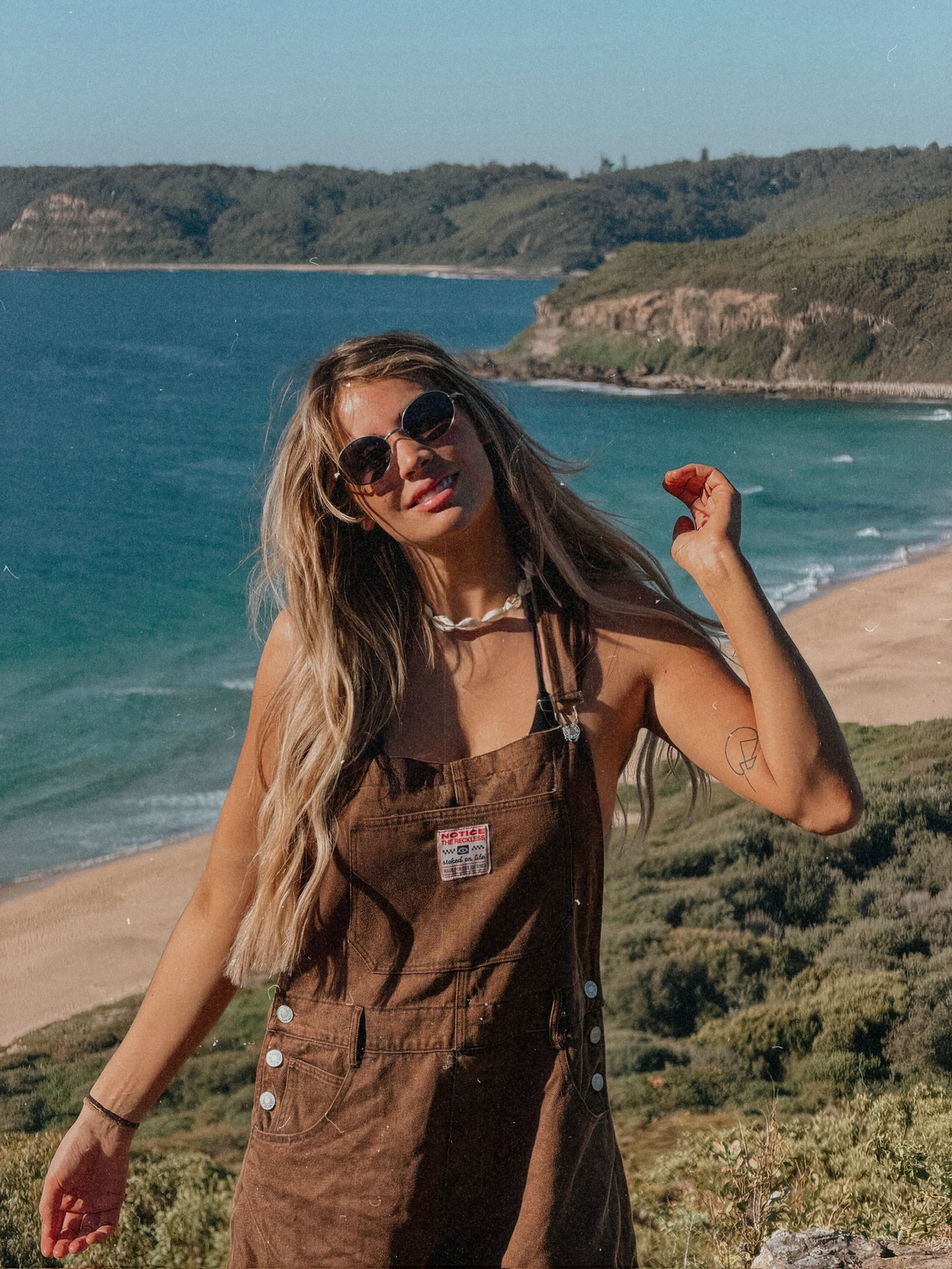 Woman wearing brown short overalls with relaxed fit and lightweight feel at the beach