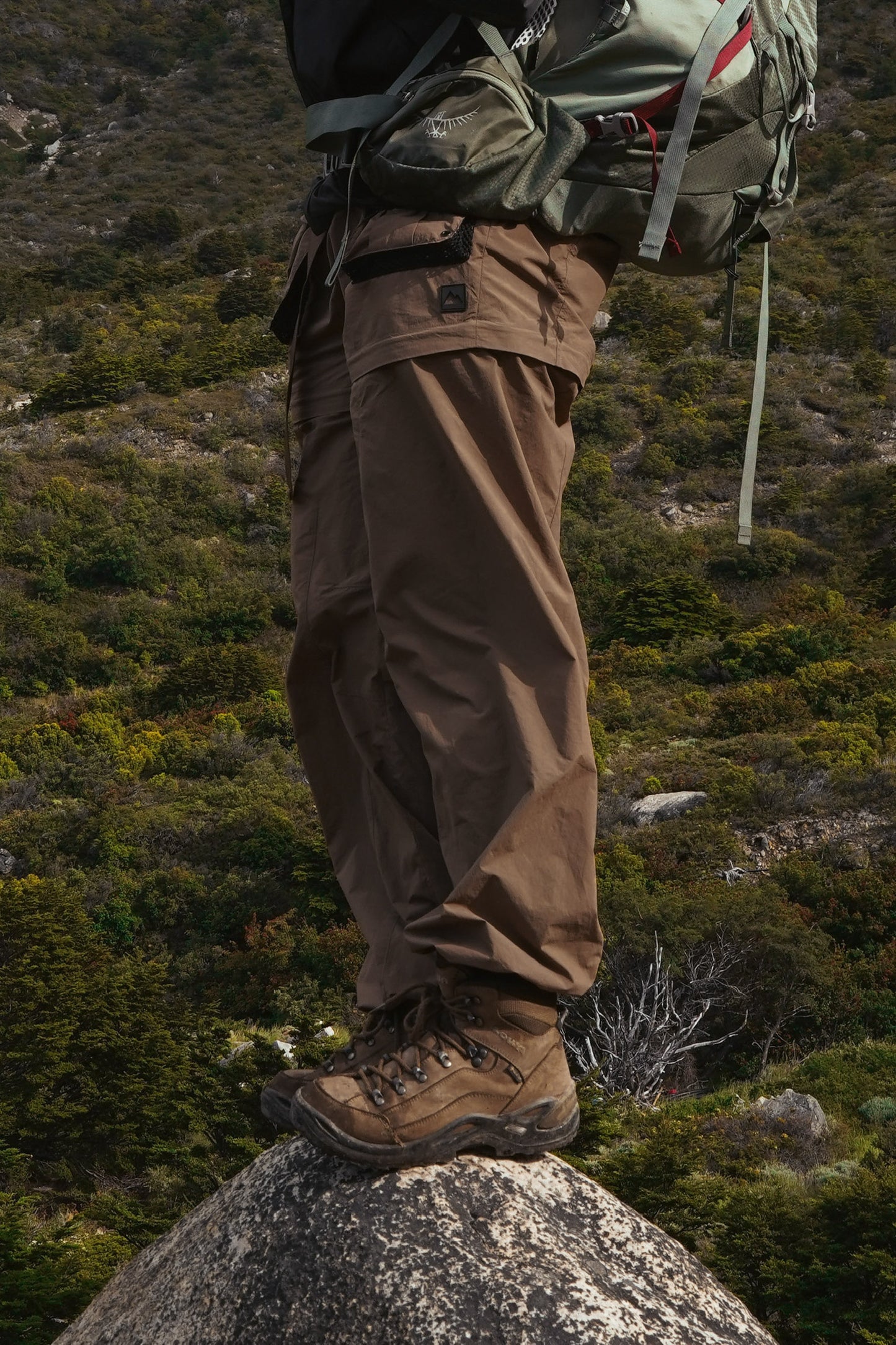 Women's walnut convertible hiking pants with side cargo pockets worn outdoors on rocky terrain