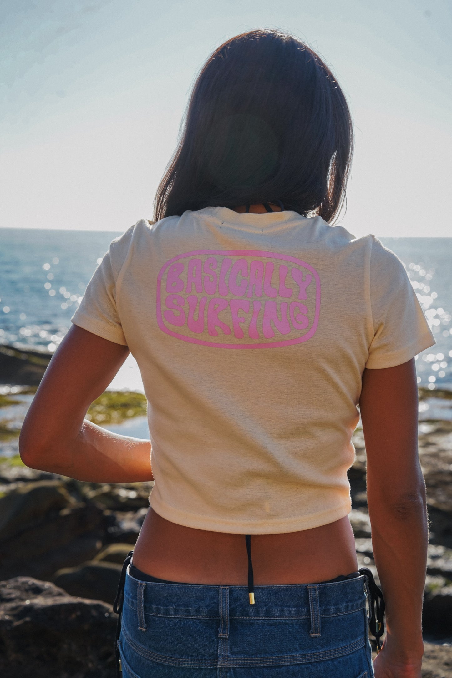 Woman wearing light yellow cotton baby tee with cropped fit and surf style design